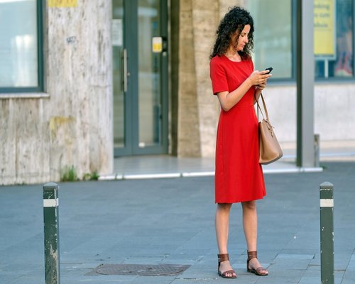 Person looking out of a bus window over a city street, holding a smartphone